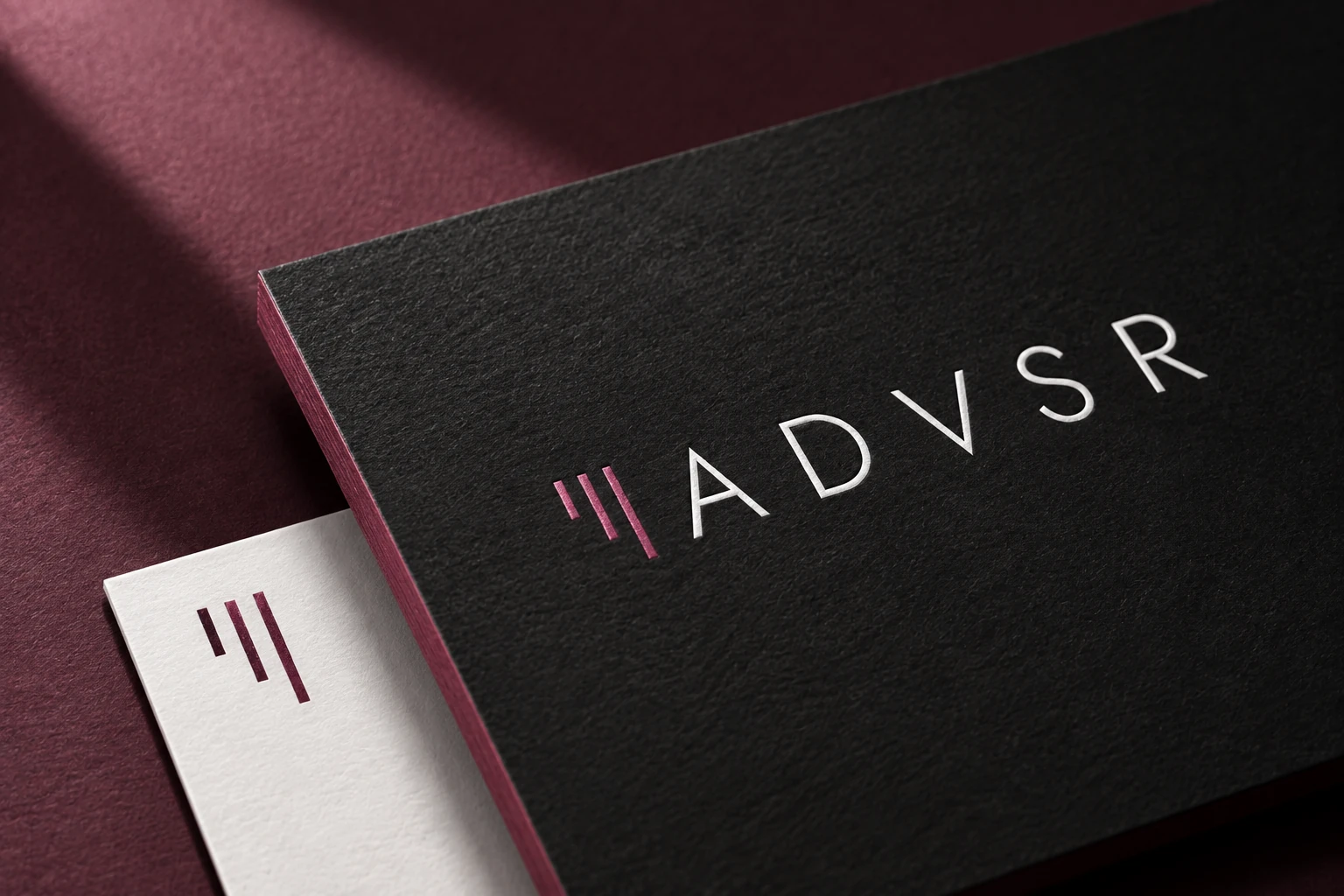 ADVSR business card concept on textured graphite and white paper with wine accents.